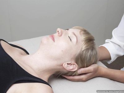 A woman lying on a couch receiving a Craniosacral Therapy treatment
