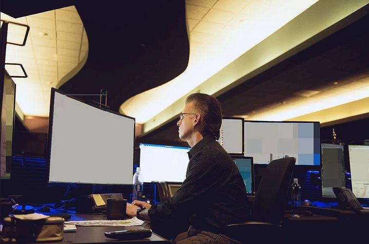 911 Dispatcher Dispatching Emergencies at a Multi-Screen Computer.