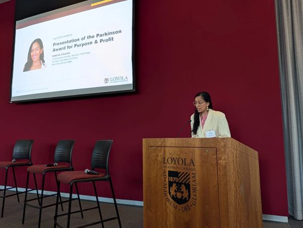 Mireya Fouche presenting at Loyola University with projected slide on Parkinson Award.