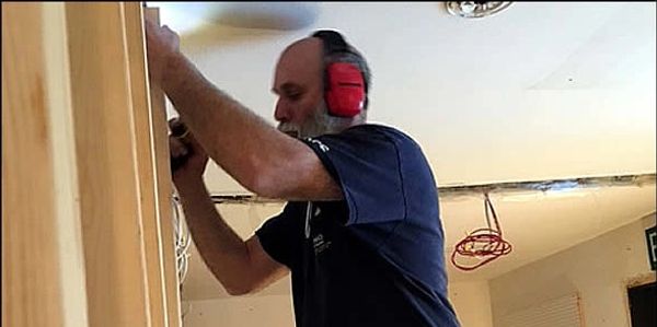 Man using a power drill indoors with ear protection.