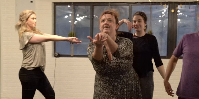 Three women practicing dance or acting indoors.