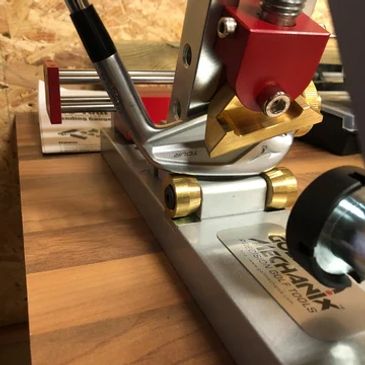 A golf club held in a precision fitting tool on a wooden workbench. loft and lie adjustments, custom fitting and golf club repairs