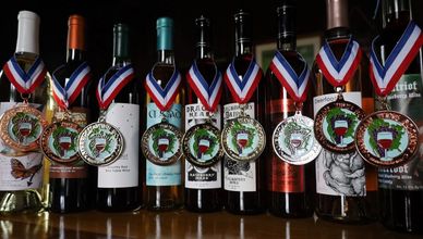 Row of wine bottles with awards around the bottle necks.