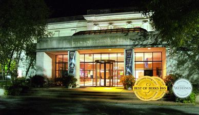 Front of lit up building with many windows. Image pictures two gold circles indicating awards.