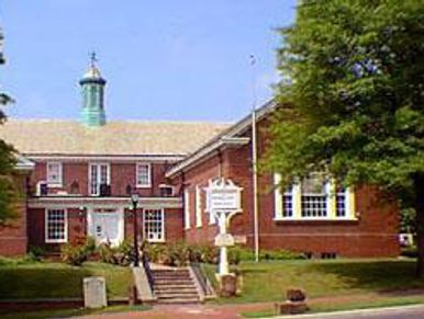 Large brick mansion with white windows and bell tower.