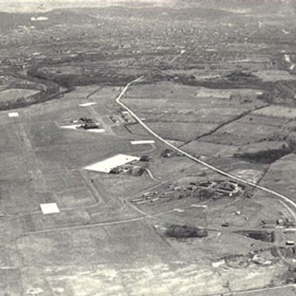 Black and white aerial picture of airport; features runways.