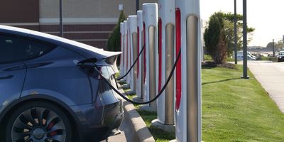 Electric cars charging at a row of Tesla Supercharger stations.