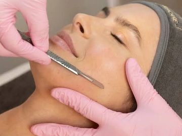 A person receiving a facial treatment with a skin scraper.
