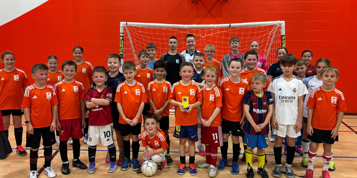 Youth soccer team posing indoors with a trophy.