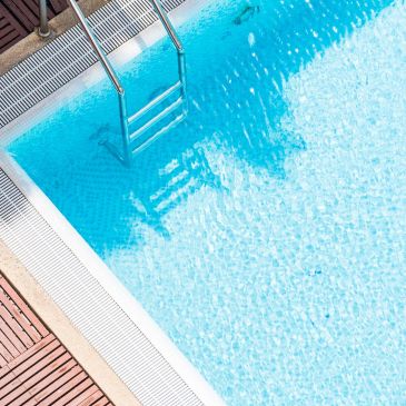 Escalera metálica en piscina con agua clara.