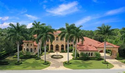 Luxurious Mediterranean-style mansion with palm trees and fountain.