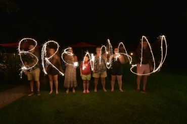 People spell 'BRENNA' with sparklers at night.