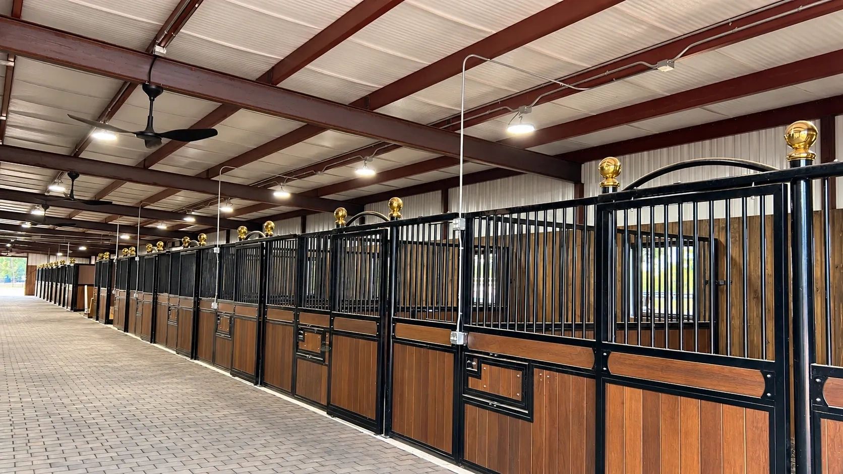 Empty modern horse stable with wooden and metal stalls.