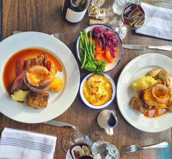 Traditional Sunday roast meal with vegetables and wine.
