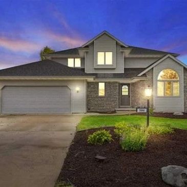 an elegant suburban home at sunset in the summer time.