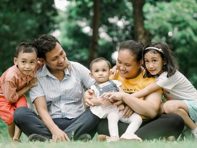 a family of five smiles and hugs one another 