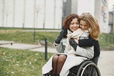 Two women, one standing and one in a wheelchair, hug