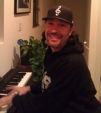 Man smiling while playing keyboard at home.