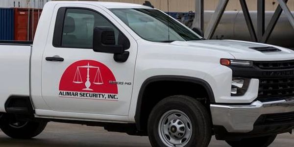 White pickup truck with Alimar Security logo parked outdoors.