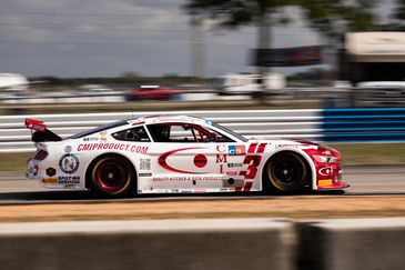 A white and red race car speeding on a race track.