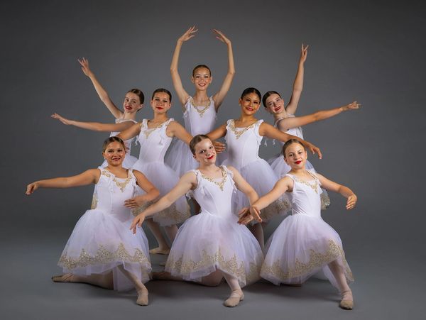 Group of young ballerinas posing in white tutus.