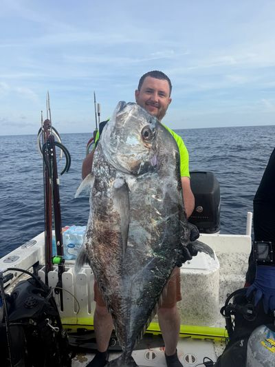 Man holding an enormous fish on a boat.