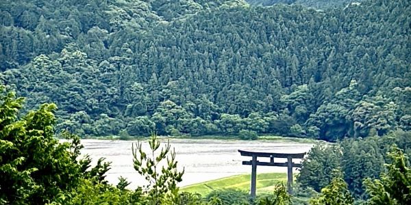 Torii gate near a dense forest and river.