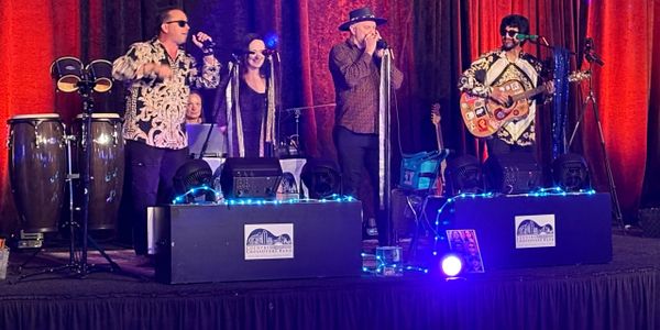 A band performs on stage with vibrant lighting and musical instruments.
