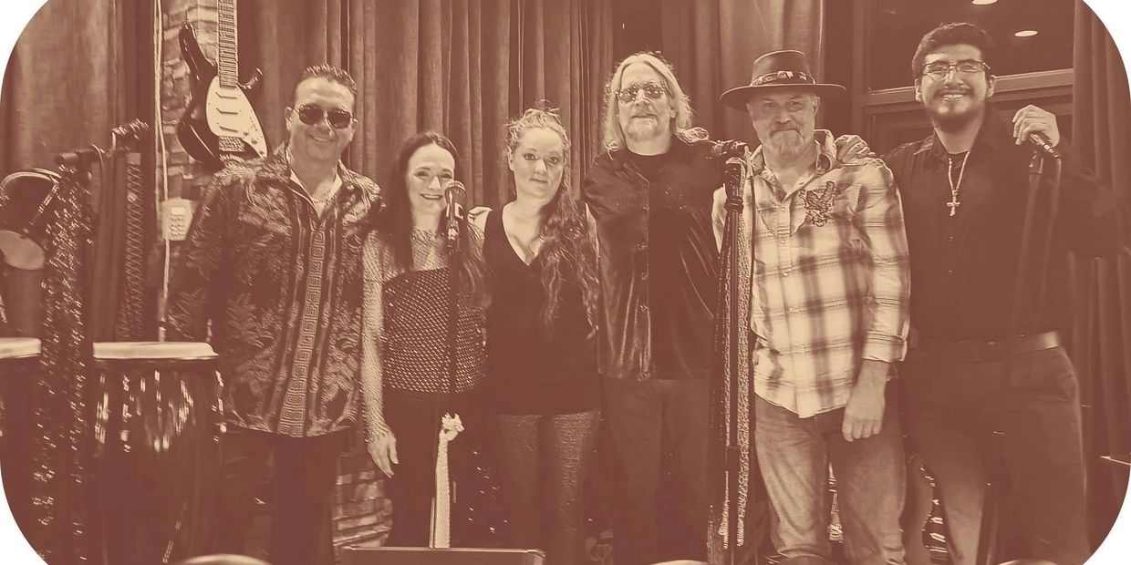 A sepia-toned photo of a six-member band posing on stage with instruments.
