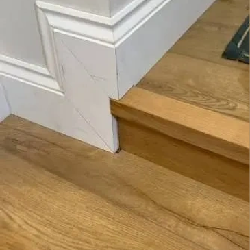 Staircase with damaged wooden step and cracked wall corner.