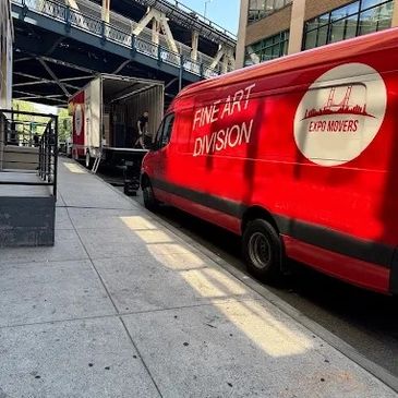 Red Expo Movers van parked near a loading dock under a bridge.