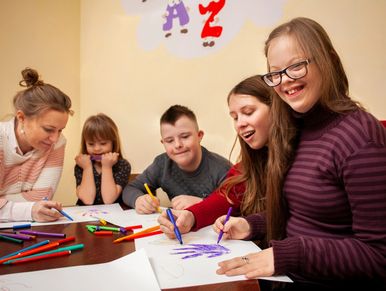 Group of people drawing and coloring together at a table.
