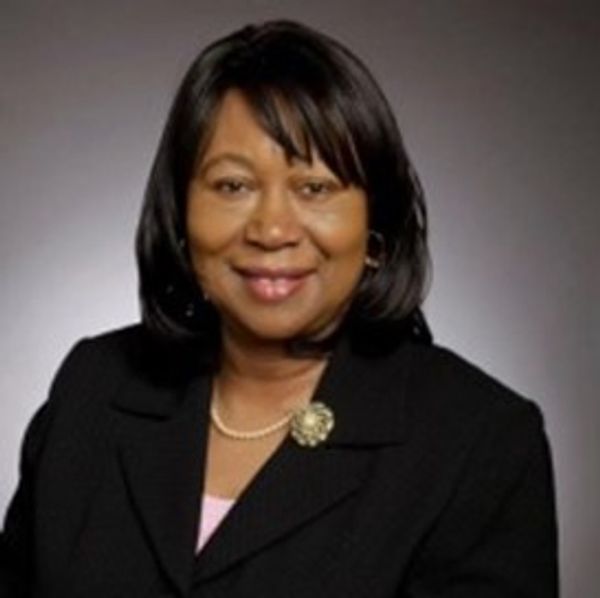Professional portrait of a smiling woman in a black suit.