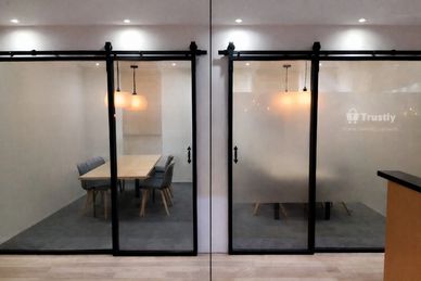 Modern office meeting rooms with glass sliding doors and pendant lights.