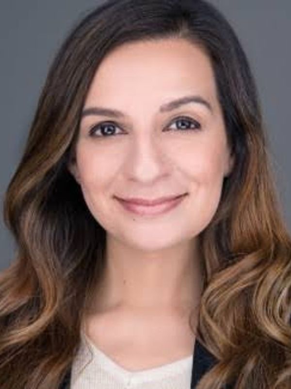 Smiling woman with wavy brown hair and natural makeup.