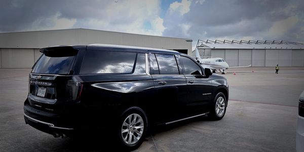 Black SUV parked near a private jet on an airport tarmac.
