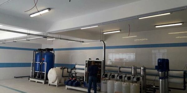 Industrial water treatment machinery in a clean facility with a worker inspecting it.