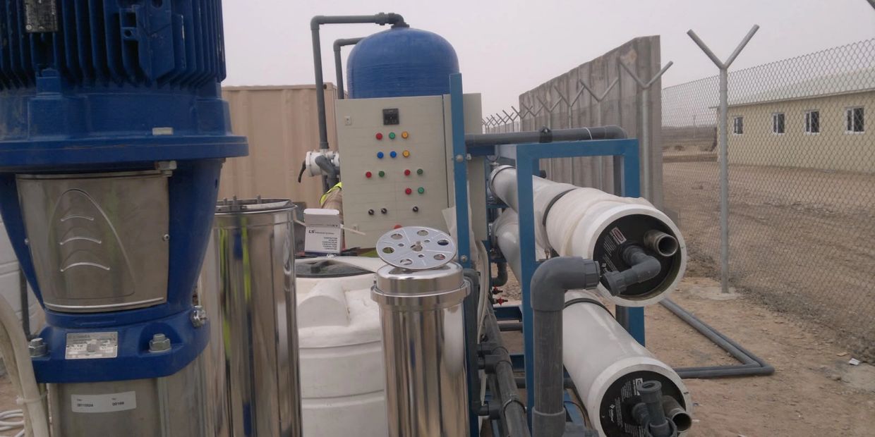 Industrial water filtration system with pipes and control panel in an outdoor setting.
