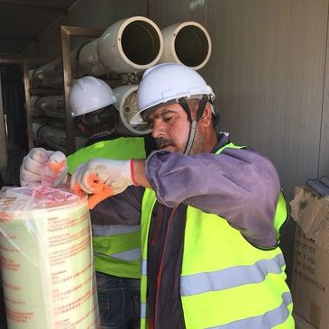 Worker in safety gear handling packaged materials indoors.