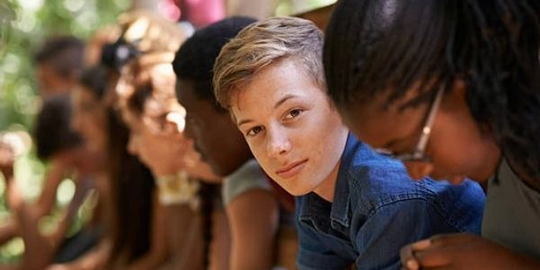 A young man looking at the camera while others look away.