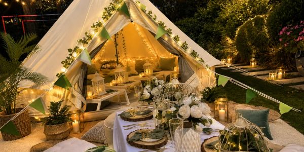 Cozy outdoor tent setup with elegant dinner arrangement and warm lights.