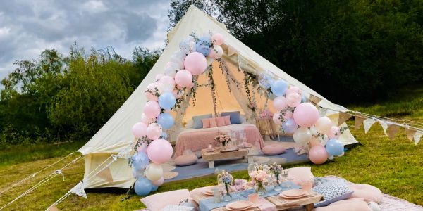 Decorated tent with pastel balloons for outdoor celebration.