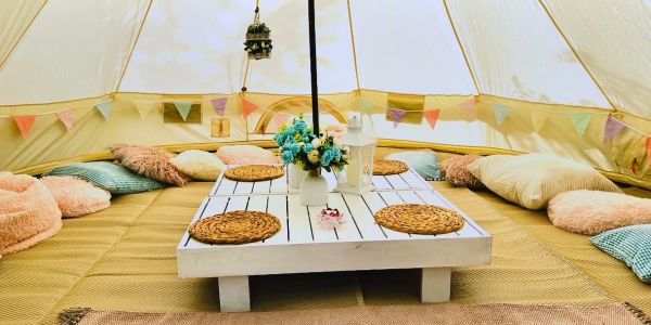 Cozy tent interior with cushions and a low table.
