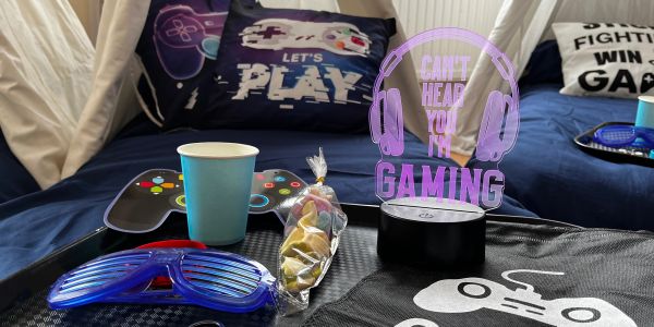 Gaming-themed setup with glasses, a cup, candy, and glowing sign.