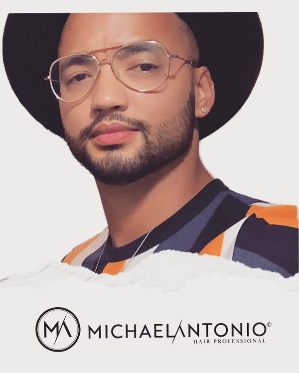 Stylish man with glasses and a hat, promoting Michael Antonio Hair Professional.