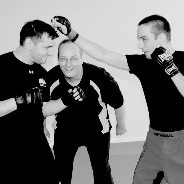 Tom Ridgeway posing with 2 students in his self-defense training class of Boxing/JKD/Kickboxing.