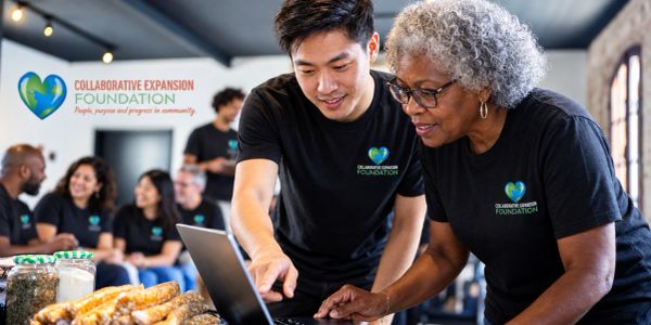 Two volunteers working together on a laptop at Collaborative Expansion Foundation.