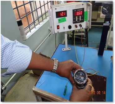 Person testing an electronic device with a digital meter and control panel.