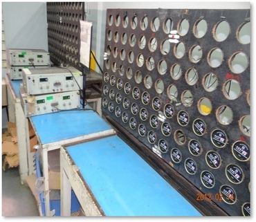 Electrical testing setup with multiple meters and devices on blue workbenches.