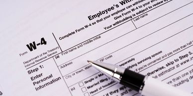 Close-up of a W-4 tax form with a pen ready to fill personal information.